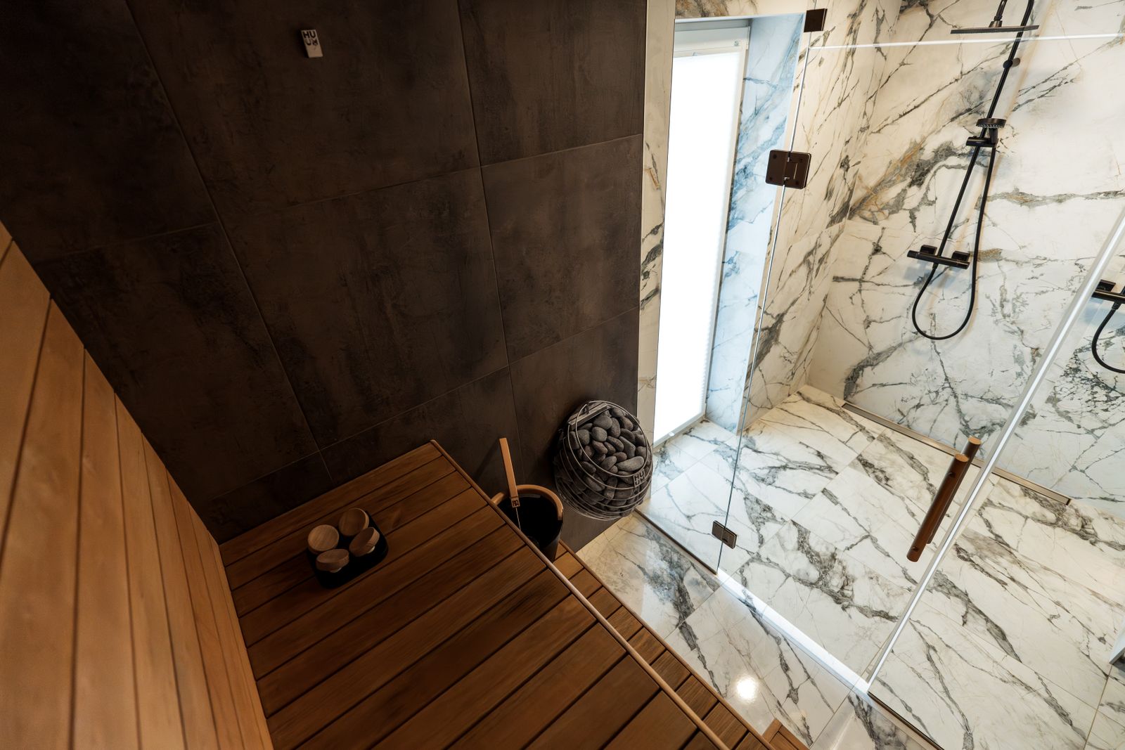 A glass-enclosed wet room with a bench and a linear drain