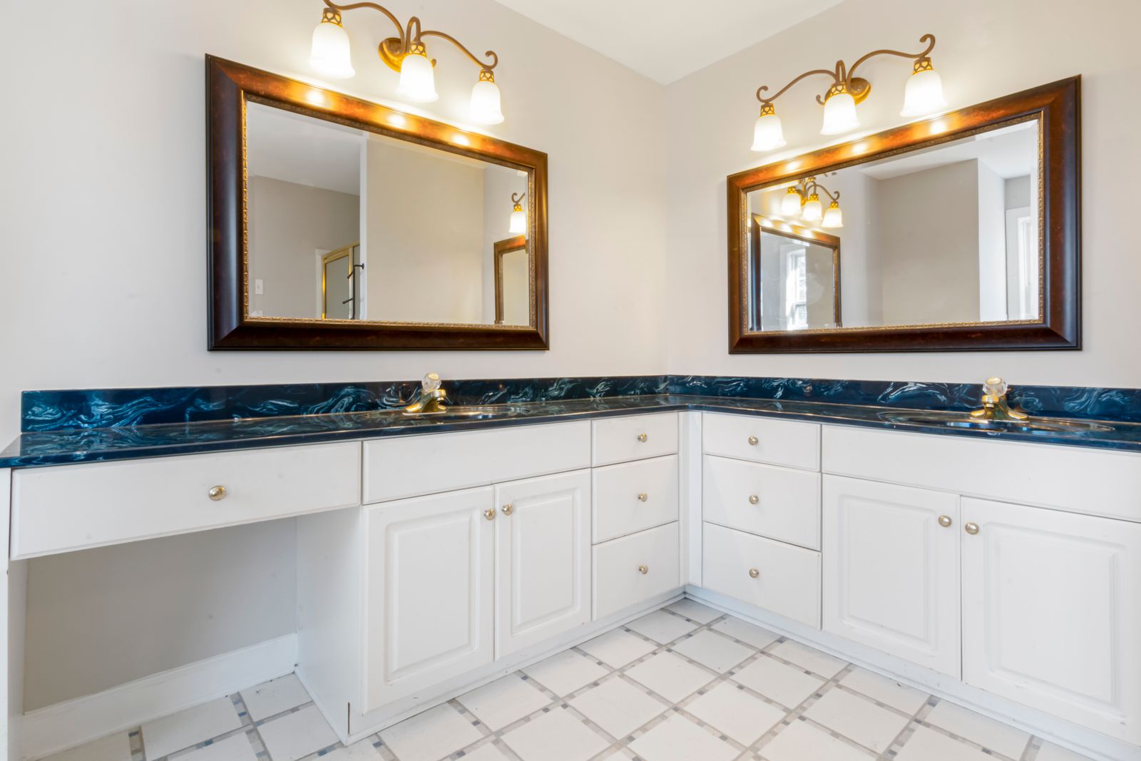 A double vanity with dual mirrors and warm lighting